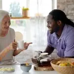 Home 5 Smiling healthcare worker supporting an elderly resident in a long-term care community